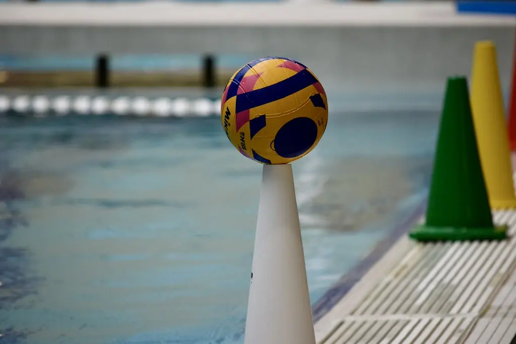 A water polo ball resting on a cone at the edge of the pool